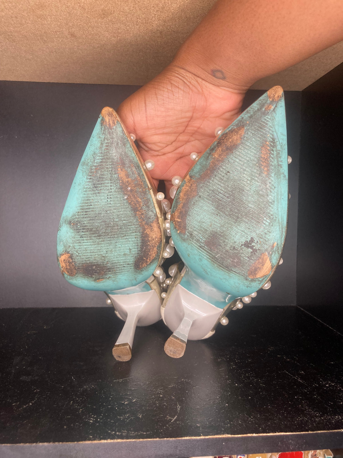 A pair of clear pointed-toe high heels decorated with white faux pearls